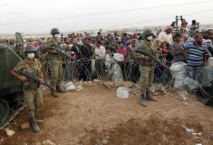 Χιλιάδες Κούρδοι της Συρίας περιμένουν πίσω από τους φράχτες στα σύνορα για να περάσουν στη Τουρκία, κοντά στη τουρκική πόλη Σουρούκ στην επαρχία Σανλιούρφα, στις 27 Σεπτέμβρη του 2014