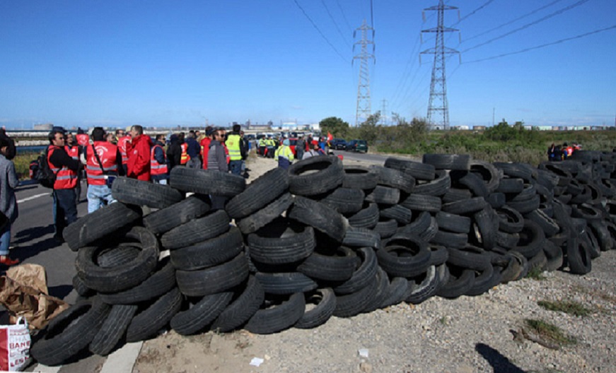 Striking union members discuss near a pile of tires as they block the entrance of a road leading to a refinery near Fos sur Mer, southern France, Monday, May 23, 2016.  Union-led blockades of French depots and oil refineries have led to fuel shortages and police action. (AP Photo/Claude Paris)