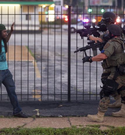 A man backs away as law enforcement officials close in on him and eventually detain him during protests over the death of Michael Brown, an unarmed black teenager killed by a police officer, in Ferguson, Mo.