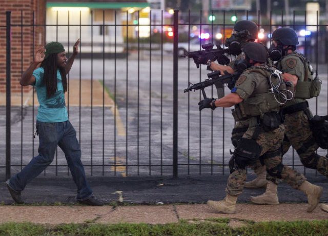 A man backs away as law enforcement officials close in on him and eventually detain him during protests over the death of Michael Brown, an unarmed black teenager killed by a police officer, in Ferguson, Mo.