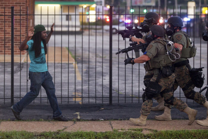 A man backs away as law enforcement officials close in on him and eventually detain him during protests over the death of Michael Brown, an unarmed black teenager killed by a police officer, in Ferguson, Mo.