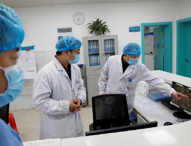 FILE PHOTO: Doctors look at a screen that shows the ward where patients who are infected with the coronavirus are treated at the First People’s Hospital in Yueyang