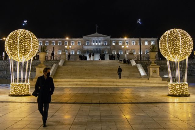 People wearing protective face masks make their way on the Christmas-decorated Syntagma square, during the coronavirus disease (COVID-19) pandemic, in Athens