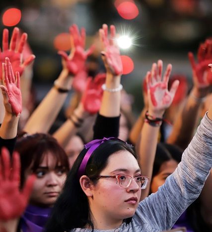Women raise their hands as they protest against gender violence and femicide in Puebla