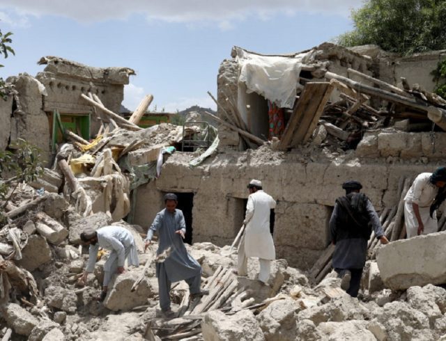 Afghan men search for survivors amidst the debris of a house that was destroyed by an earthquake in Gayan