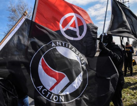 Members of the Great Lakes anti-fascist organization (Antifa) fly flags during a protest against the Alt-right outside a hotel in Warren, Michigan