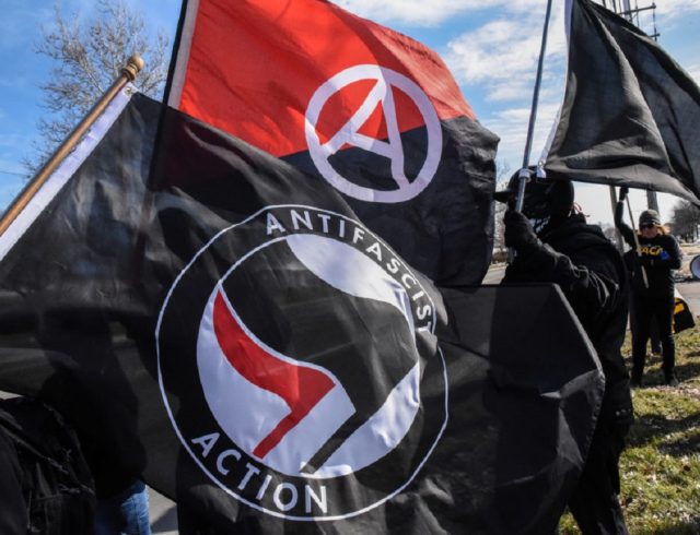 Members of the Great Lakes anti-fascist organization (Antifa) fly flags during a protest against the Alt-right outside a hotel in Warren, Michigan