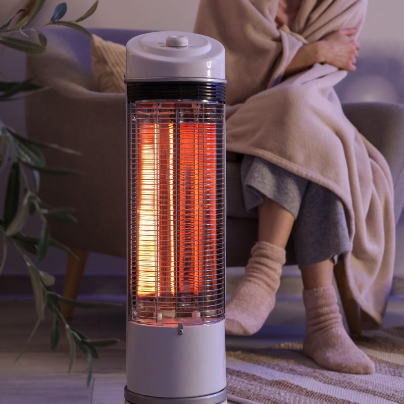 Young,Woman,With,Electric,Heater,And,Blanket,Sitting,On,Armchair